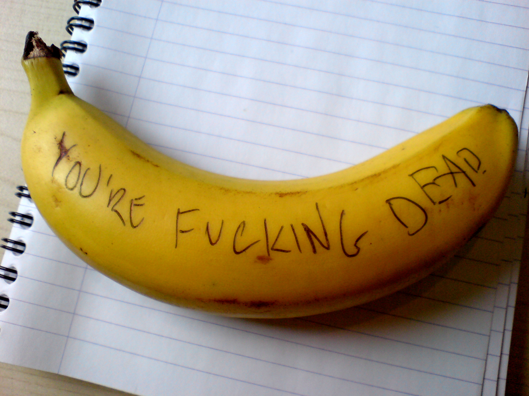 Photo of a banana with the words "You're fucking dead" written on it