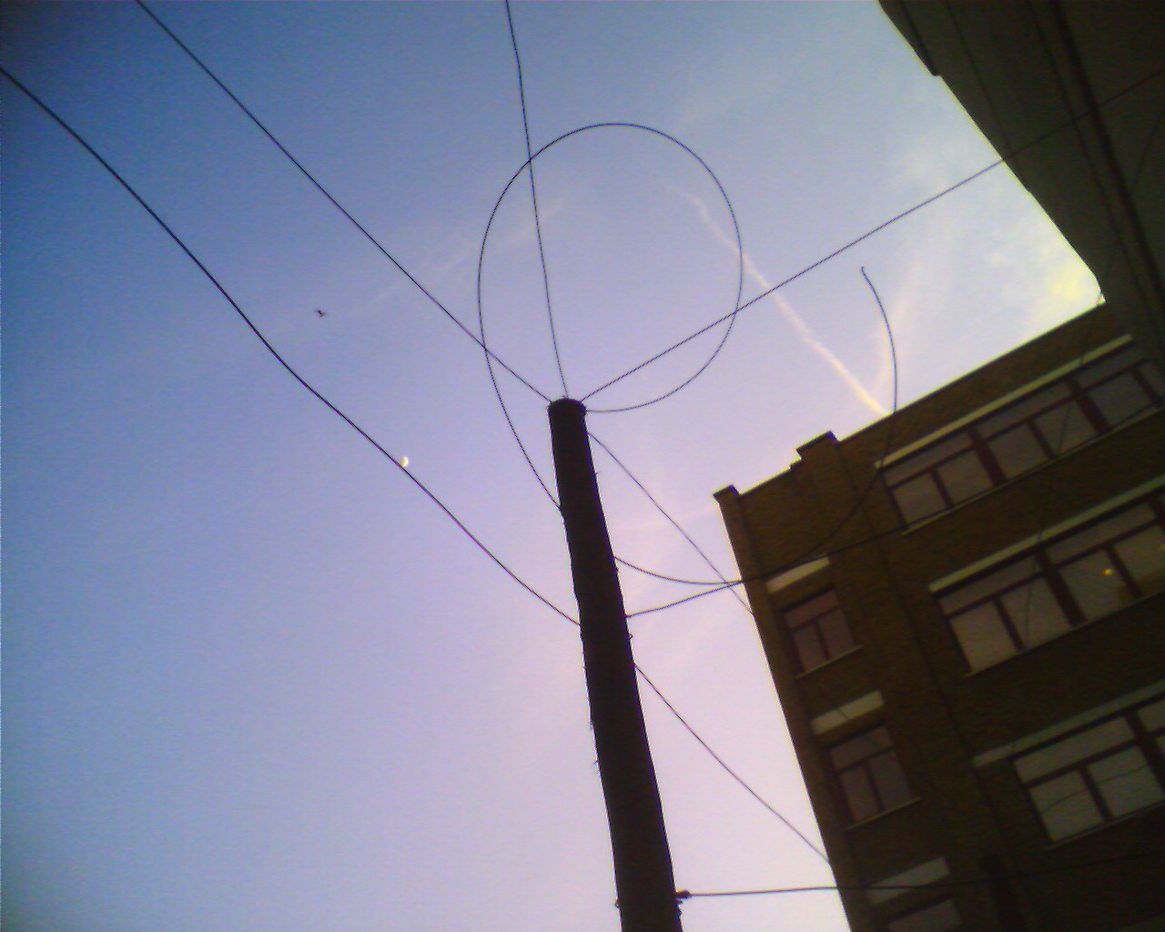 Lofi photo of twirling telegraph pole wires against a hazy sky